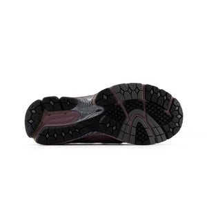 Bottom view of a New Balance shoe displaying the complex black and dark grey rubber outsole, featuring textured traction pods and a supportive midfoot bridge for grip