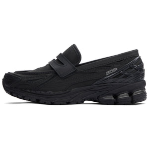 A lateral profile showcasing the New Balance 1906L Black Leather hybrid loafer with its smooth leather finish and refined upper structure.