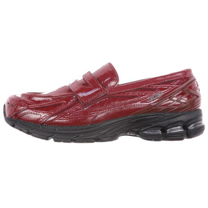 A lateral profile showcasing the New Balance 1906L Patent Burgundy hybrid loafer with its glossy finish and black sole.