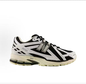 New Balance shoes 1906R sneaker in black and metallic silver, medial profile view displaying white synthetic leather overlays, N-lock support lace webbing, and N-ergy shock-absorbing soles.