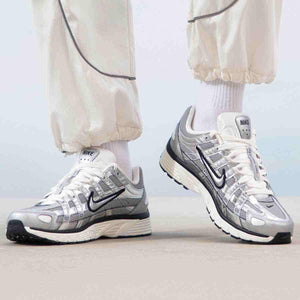 The lifestyle shot highlights Nike Shoes elegance, showcasing the حذاء نايك الأصلي مع حذاء P-6000 لون فضي ميتاليك بتصميم رياضي عصري ضمن أفضل موديلات شوز نايك وتصاميم nike schuhe.