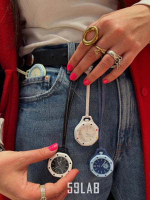 A person wearing two Audemars Piguet x Swatch Royal Pop pocket watches attached to a belt loop, showcasing them styled as waist accessories.