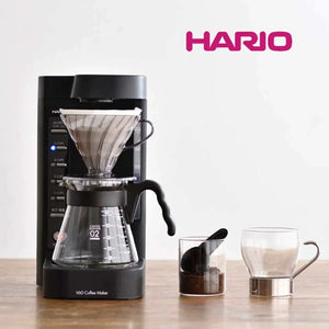 صانعة القهوة المفلترة الأوتوماتيكية Hario V60 باللون الأسود main setup view مع إبريق صب زجاجي وملحقات القياس.