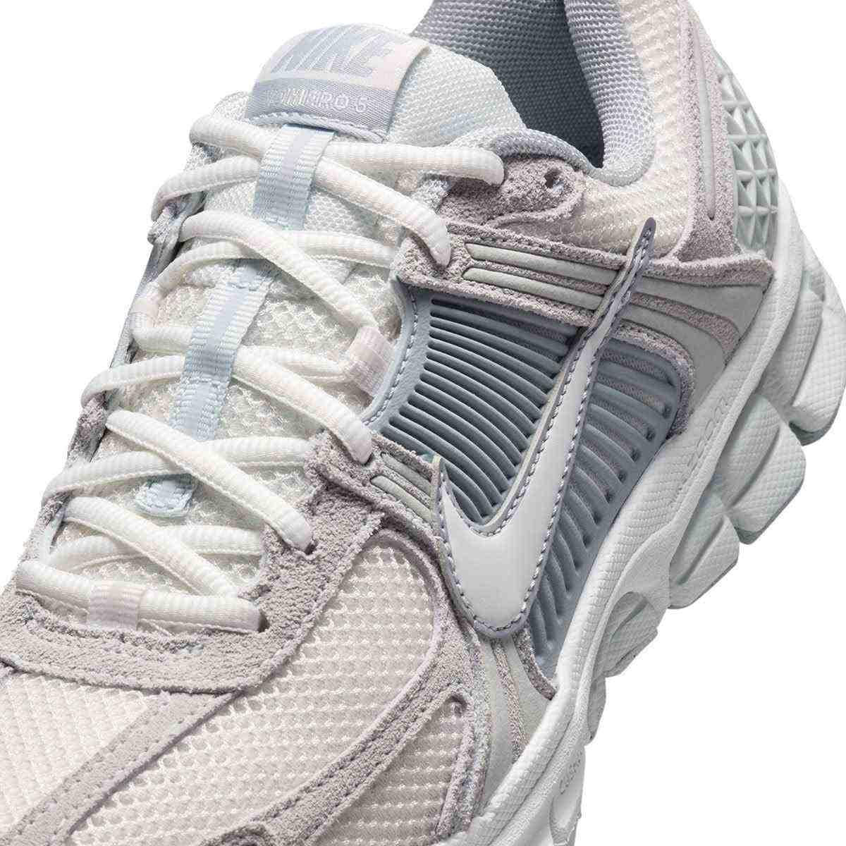 حذاء رياضي Nike Vomero 5 رمادي فاتح بتفاصيل عاكسة.