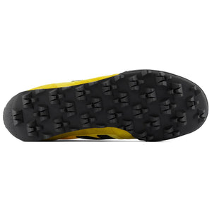 Bottom outsole view of yellow and black New Balance RC30 shoes, featuring a black rubber tread pattern with exaggerated angular studs across the entire sole.
