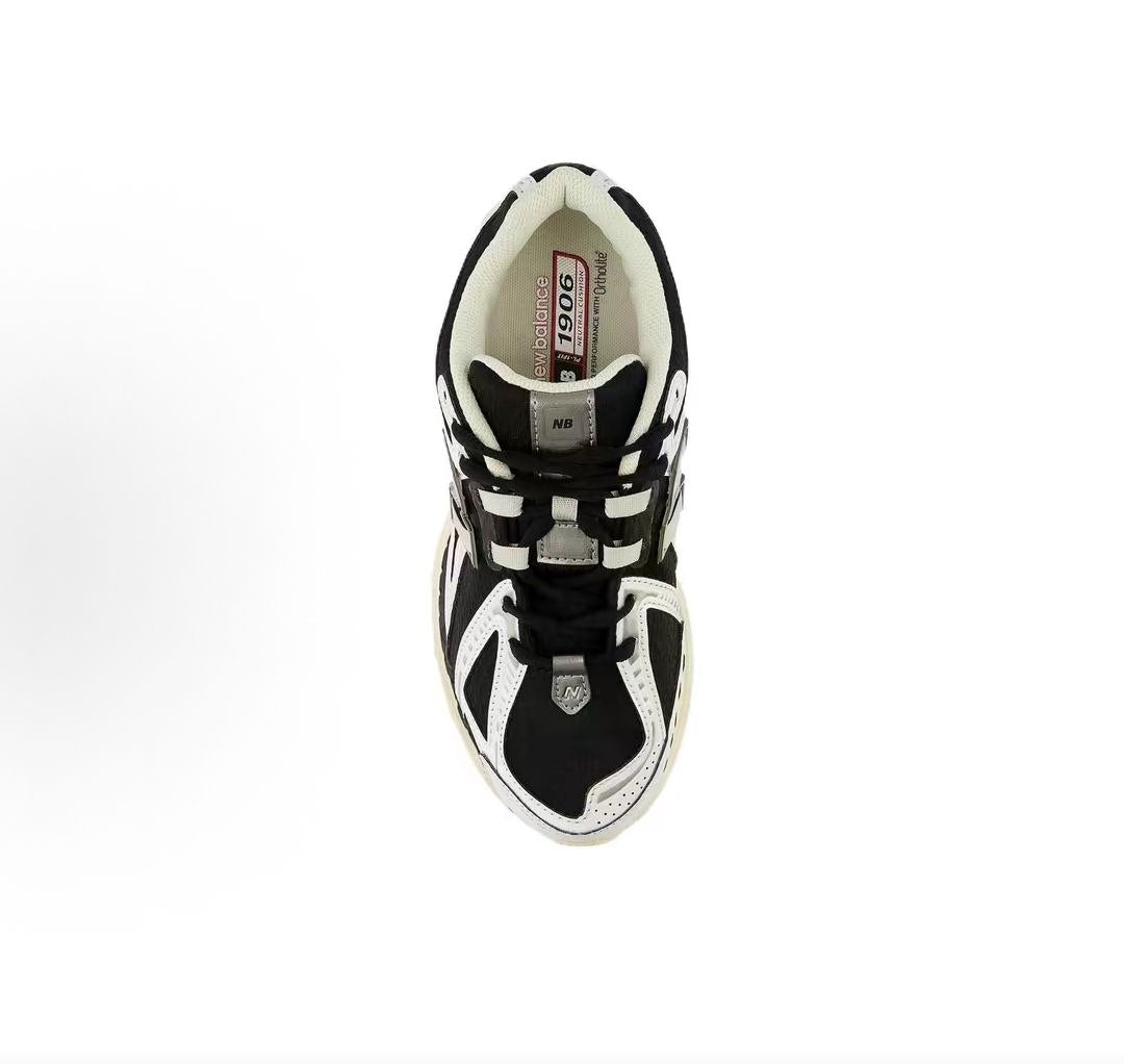 New Balance shoes 1906R running sneaker in black and white, top-down perspective showing black mesh uppers, white leather structural toe overlays, tongue lace-loop branding, and Ortholite inner soles.