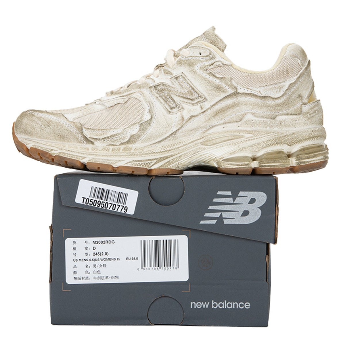 حذاء New Balance 1906R بلون بيج بتصميم فني غير تقليدي، بمواد خشنة ومظهر متآكل متعمد.