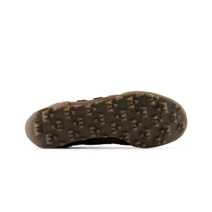 Bottom outsole view of Donald Glover x New Balance RC30 "Golden Hour" shoes, featuring a brown rubber tread pattern with exaggerated angular studs across the entire sole.