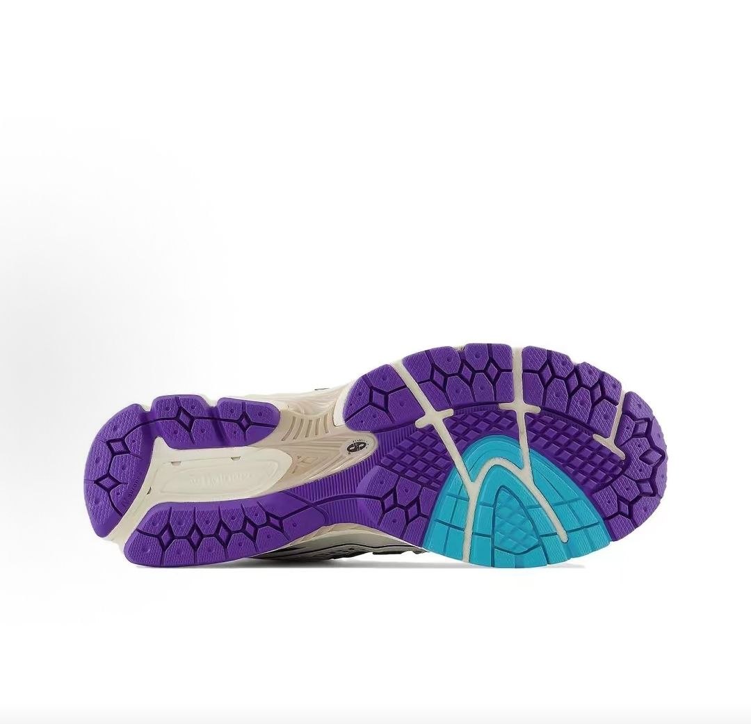 Bottom outsole view of New Balance shoes 1906R model, featuring a vibrant purple and teal rubber tread pattern with a cream Stability Web arch support insert.