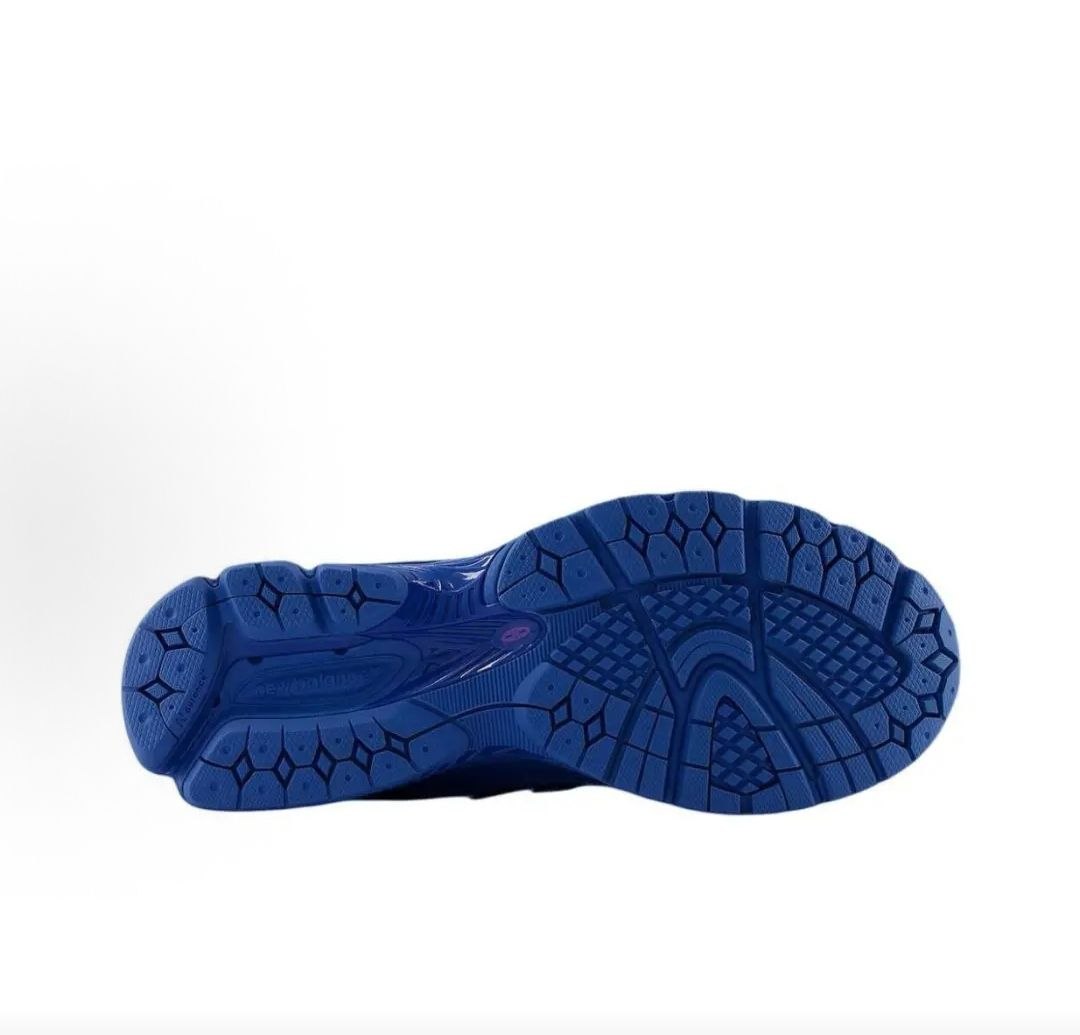 Bottom outsole view of blue polka dot New Balance shoes 1906R model, featuring a solid royal blue rubber tread pattern with a matching midfoot Stability Web shank and purple branding accent.