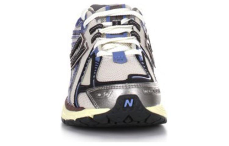 Front toe-on view of white, blue, and purple New Balance shoes 1906R model, displaying breathable white mesh toe box with metallic silver and navy overlays, blue tongue accents, white laces, and black rubber toe cap featuring the blue N logo.