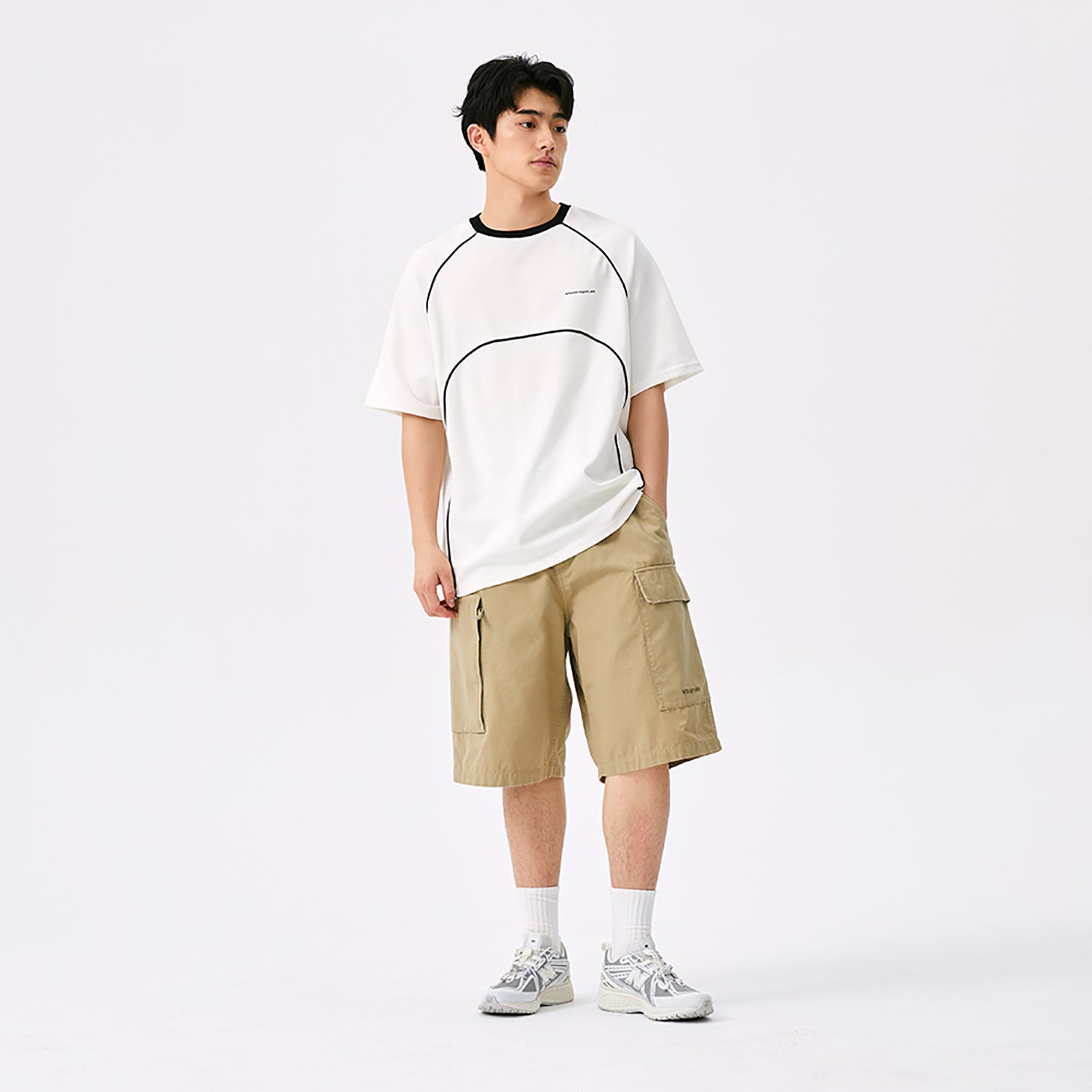 Full-body model view featuring grey and white New Balance shoes 1906R styled in a streetwear outfit.