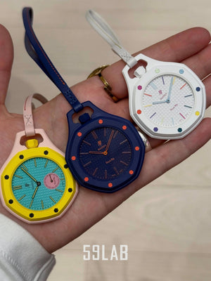 Close-up of yellow, blue, and white Audemars Piguet x Swatch Royal Pop pocket watches held by their matching leather straps.