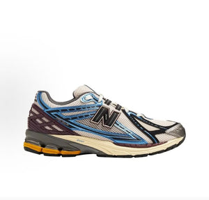 Medial side profile view of white, metallic blue, and purple New Balance shoes 1906R.