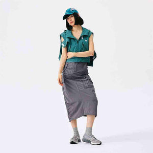 A full-body view of a female model styling the New Balance 1906L grey loafer with a modern, oversized green shirt and grey skirt. Showcases the versatile fashion-forward look of new balance 1906l women (نيو بالانس 1906L رمادي للنساء والرجال).