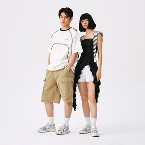 New Balance shoes 1906R model in grey and white colorway, full-body lifestyle view demonstrating outfit styling with oversized t-shirt, khaki cargo shorts, and crew socks.