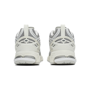 New Balance shoes 1906R model in grey and white colorway, rear heel perspective displaying off-white TPU support cages, fabric heel pull tabs, textured mesh collars, and N-ergy shock-absorbing midsoles.