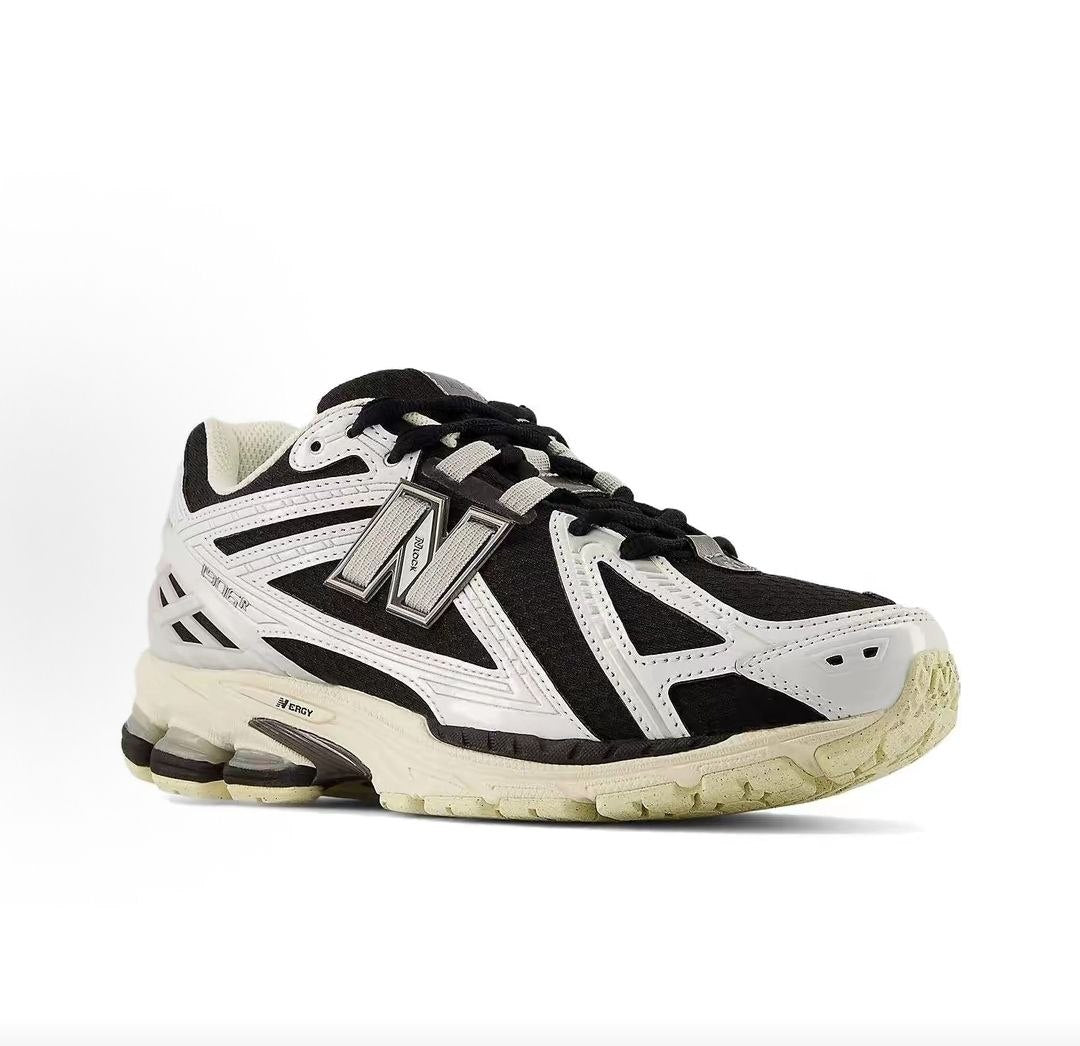 New Balance shoes 1906R model, three-quarter perspective displaying black mesh upper, white structural overlays, N-lock lacing system, and N-ergy shock-absorbing soles.