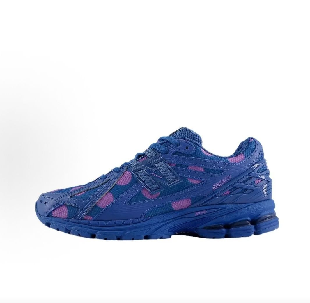New Balance shoes 1906R running sneaker in blue polka dot pattern, lateral profile view showcasing blue and purple mesh uppers, structural cage overlays, N-lock support lace webbing, and N-ergy shock-absorbing soles.