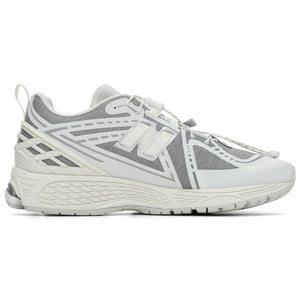 New Balance shoes 1906R running sneaker in grey and white colorway, medial profile view displaying breathable mesh uppers, structural white synthetic cage overlays, toggle cord lacing system, heel pull tab, and shock-absorbing N-ergy midsoles.