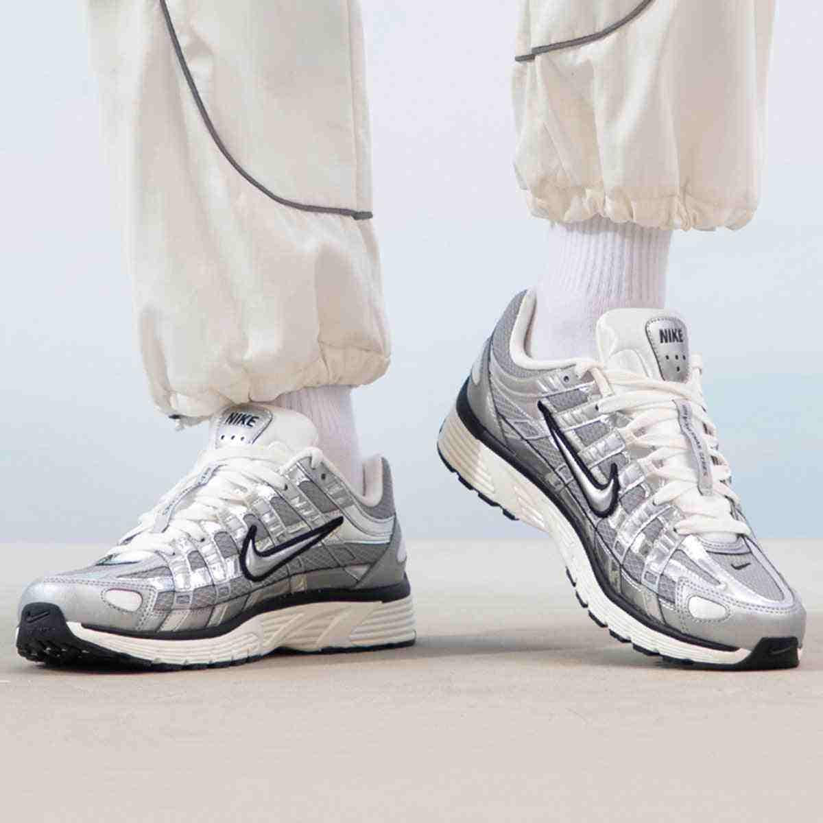 The lifestyle shot highlights Nike Shoes elegance, showcasing the حذاء نايك الأصلي مع حذاء P-6000 لون فضي ميتاليك بتصميم رياضي عصري ضمن أفضل موديلات شوز نايك وتصاميم nike schuhe.