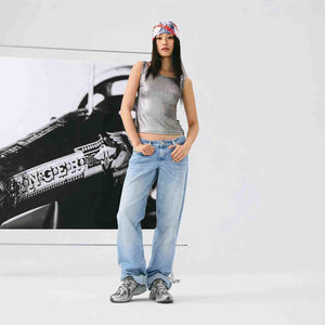 On-foot perspective of light blue jeans and dark grey New Balance running shoes