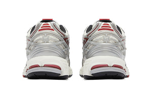 Rear heel view of a pair of white, silver, and red New Balance shoes 1906R model, featuring metallic silver molded TPU heel cages with NB branding, white mesh heel mesh, red trim accents, and off-white N-ergy cushioned midsoles with dark red heel pods.