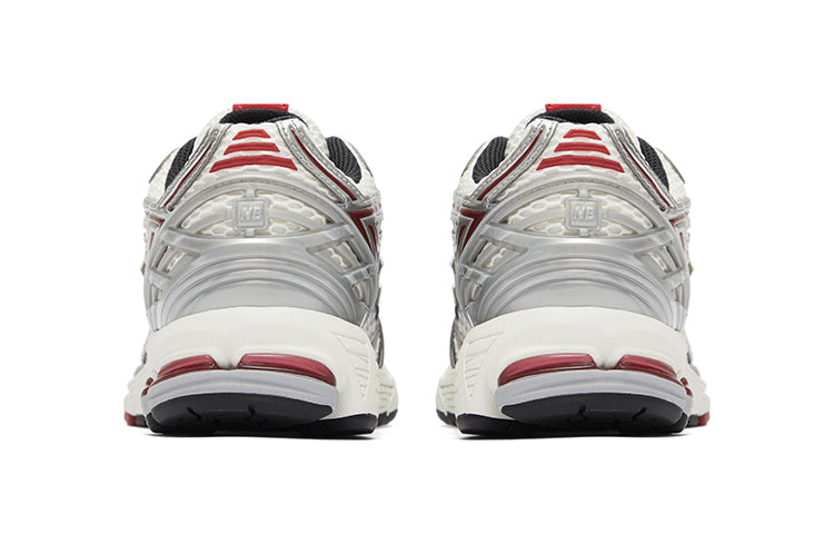 Rear heel view of a pair of white, silver, and red New Balance shoes 1906R model, featuring metallic silver molded TPU heel cages with NB branding, white mesh heel mesh, red trim accents, and off-white N-ergy cushioned midsoles with dark red heel pods.