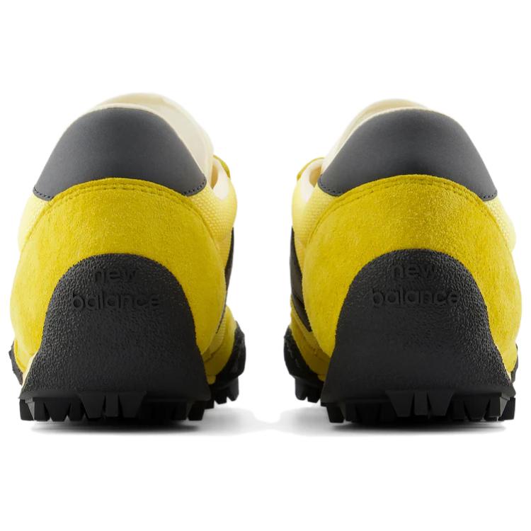 Rear heel view of a pair of yellow and black New Balance RC30 shoes, featuring bright yellow suede heel counters, dark grey leather heel tabs, and an extended black rubber outsole wrap stamped with "new balance" text branding.