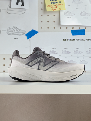 Side view profile of a grey New Balance running sneaker on a ledge against a design concept board