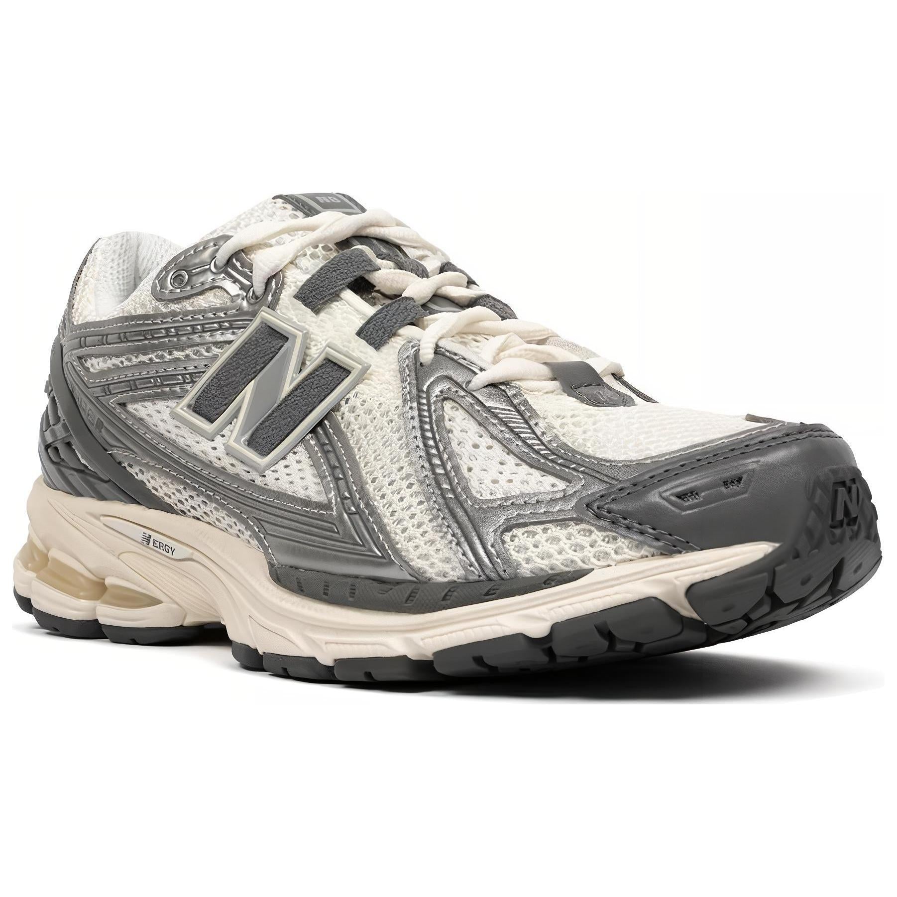 Three-quarter profile shot of metallic silver and cream New Balance shoes 1906R model, featuring breathable off-white mesh uppers, metallic silver and dark charcoal overlays, off-white laces, and an aged cream N-ergy cushioned midsole.