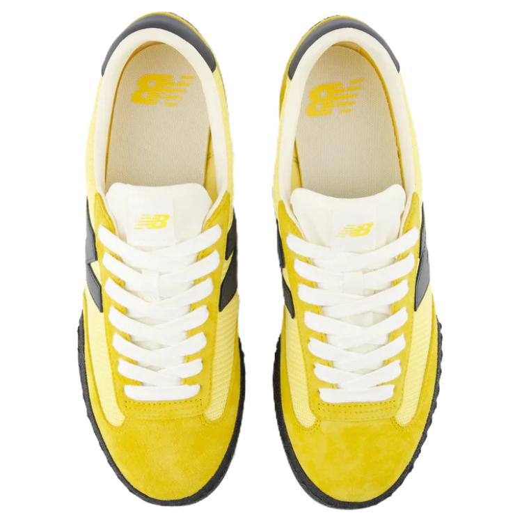 Top-down aerial view of a pair of yellow and black New Balance RC30 shoes, displaying bright yellow suede toe caps and eyestays, light yellow nylon vamps, crisp white laces, off-white nylon tongues with yellow NB logo tags, and cream-colored insoles featuring yellow printed branding.