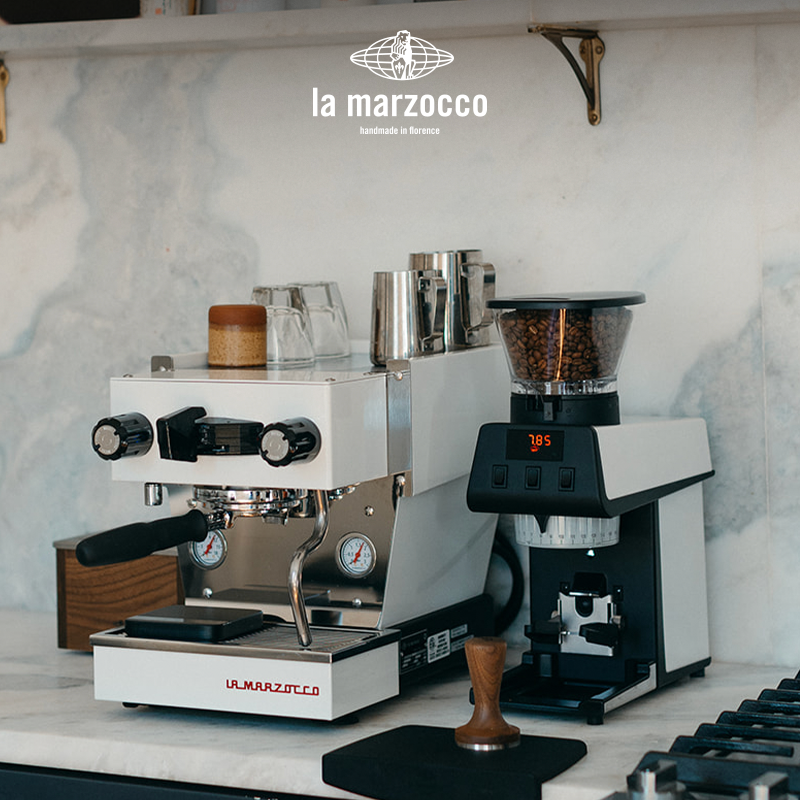ماكينة اسبريسو احترافية La Marzocco Linea Micra باللون الأبيض kitchen setup مع مطحنة القهوة المرافقة.