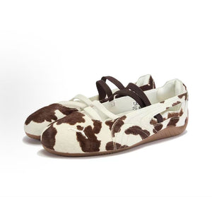 Pair of original Puma Speedcat Ballet cow print brown white shoes front angle view on white background.