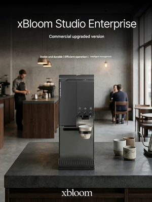 Matte black xBloom Studio Enterprise commercial automatic coffee machine placed on a dark countertop inside a modern specialty coffee shop.